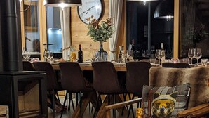 A cozy room with a wooden interior, a fireplace, a dining table set with chairs, and a large clock on the wall. - Chalet "Friwi": Mountain View, Private Terrace & Wi-Fi (Saint-Jean-de-Sixt)