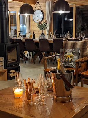 A cozy room with a wooden interior, a fireplace, a dining table set with chairs, and a large clock on the wall. - Chalet "Friwi": Mountain View, Private Terrace & Wi-Fi (Saint-Jean-de-Sixt)