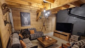 A cozy living room with a wooden ceiling, a large TV, and a fireplace. - Chalet "Friwi": Mountain View, Private Terrace & Wi-Fi (Saint-Jean-de-Sixt)