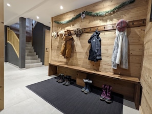 A wooden wall with hats and jackets hanging, a bench with boots, and a staircase in the background. - Chalet "Friwi": Mountain View, Private Terrace & Wi-Fi (Saint-Jean-de-Sixt)