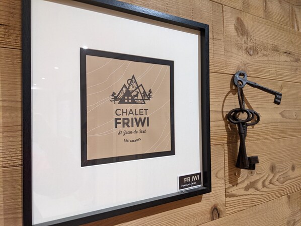 A framed picture with a mountain and house design, labeled 'CHALET FRIWI' and 'St Jean de Sixt LES ARAVIS.'