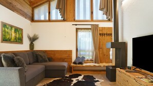 Un salón acogedor con sofá, alfombra de cuero, televisor y pared de madera.