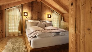 Un dormitorio tipo cabaña de madera con una cama, dos lámparas fijadas a la pared y una alfombra de piel.