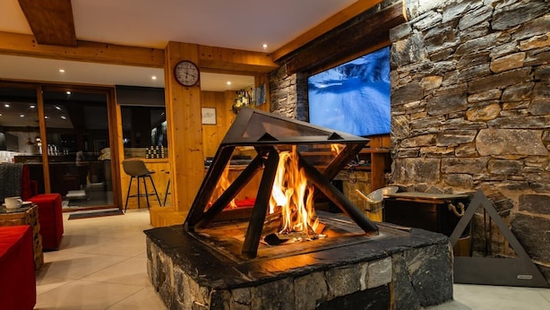 A stone fireplace with a modern design, a television mounted on a stone wall, and a wooden ceiling.