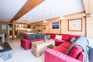 Un salon chaleureux avec un canapé rouge, une table basse en pierre et un plafond en bois.