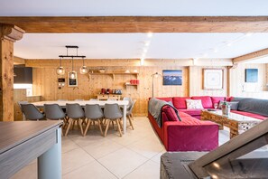 Un intérieur en bois comprenant une table à manger, des chaises, un canapé rouge et une table basse.