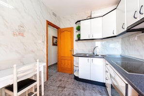 A kitchen with white cabinets, a black countertop, and a wooden door. - Villa 'Cruz' with Private Terrace, Balcony and Air Conditioning (Fernán Pérez)