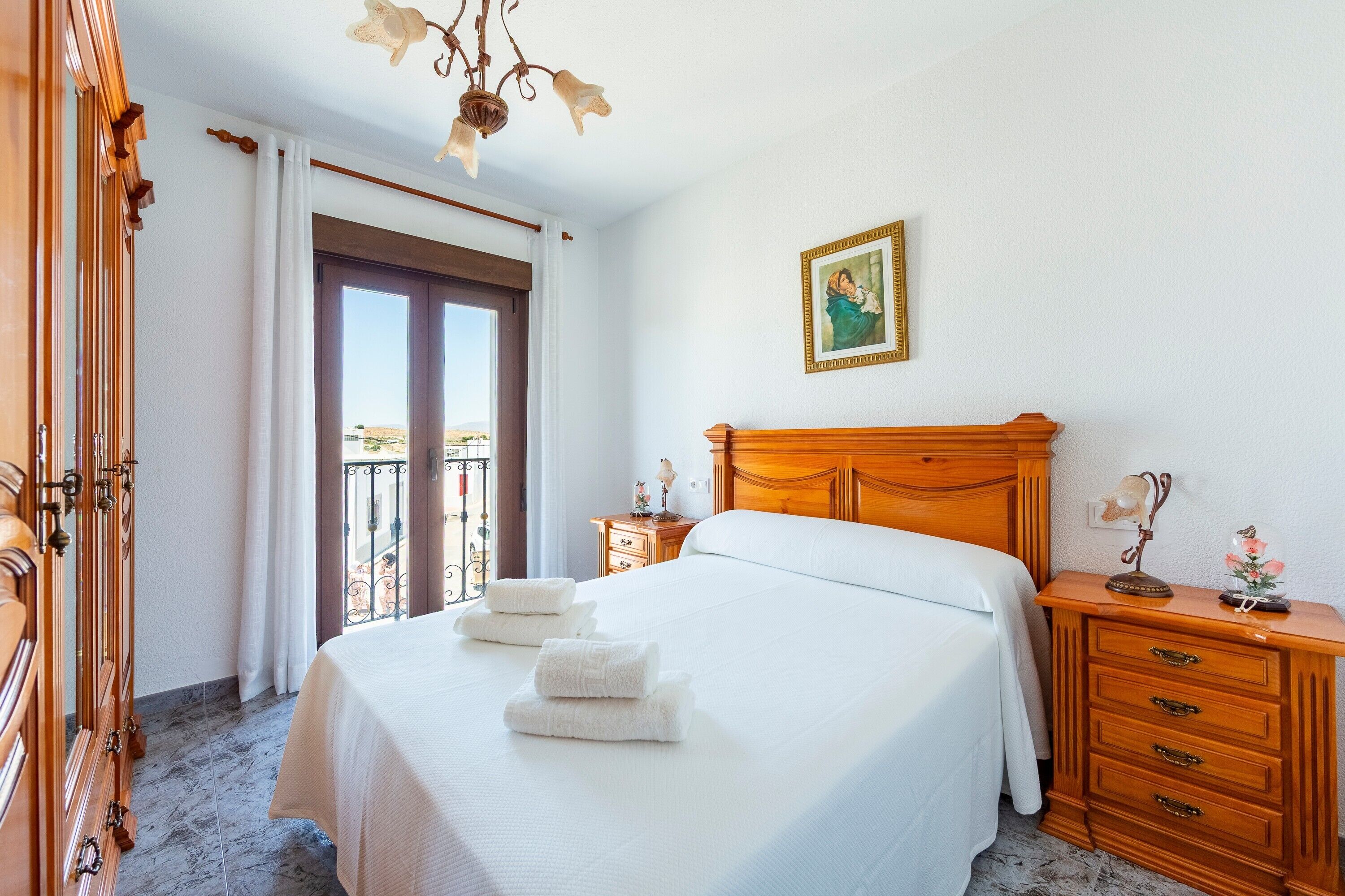Una habitación de hotel con cama, cómoda de madera y un cuadro en la pared.
