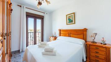 Una habitación de hotel con cama, cómoda de madera y un cuadro en la pared.