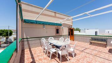 A patio with a table and chairs, a tiled floor, and a building with a green awning.