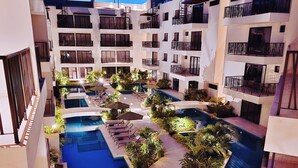 Et hotel med flere etager, en central pool, altaner og frodig beplantning.