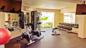 Et fitnesscenter med løbebånd, styrketræningsudstyr og spejle.
