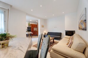 Una sala de estar con sofá, televisor y comedor con sillas y mesa.