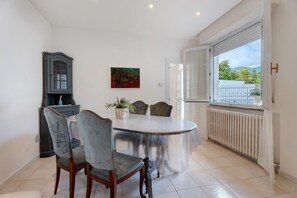 Un comedor con una mesa redonda, sillas, un armario y una ventana con vistas.