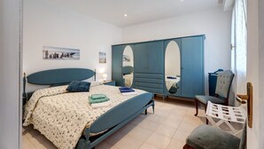 A bedroom with a bed, a wardrobe, a chair, and a small table.