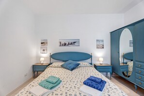 Un dormitorio con cama, dos mesitas de noche, un aparador y decoración en la pared.