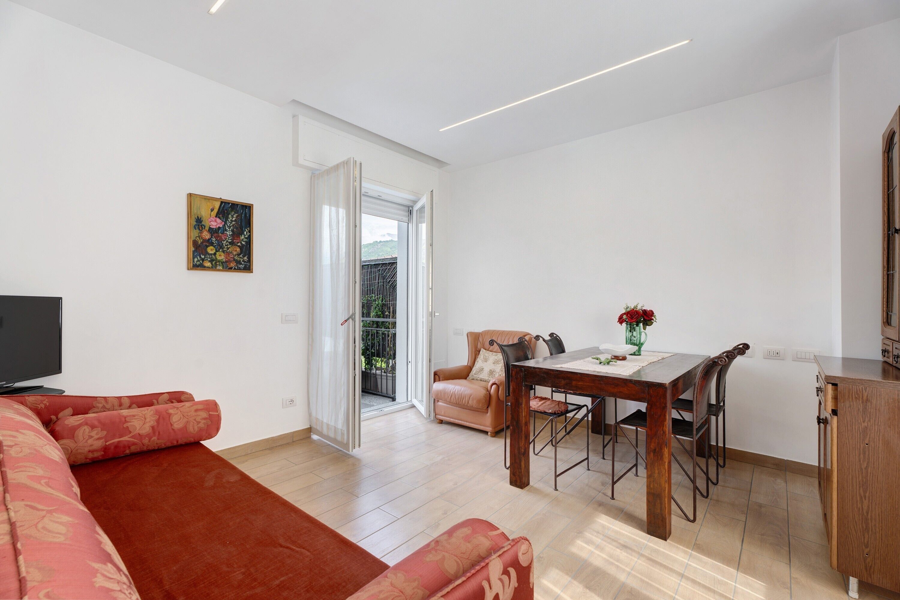 Een woonkamer met een bank, een eettafel en een televisie.
