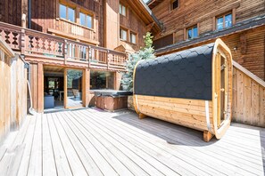 Eine Holzhütte mit einer Terrasse, einem Whirlpool und einer überdachten Sitzgruppe im Freien.