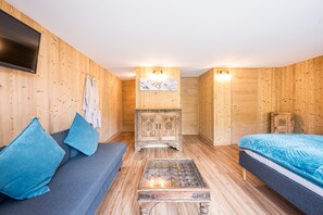 Ein Zimmer mit Holzwandverkleidung, einer Couch, einem Schrank, einem Bett und einem Fernseher.