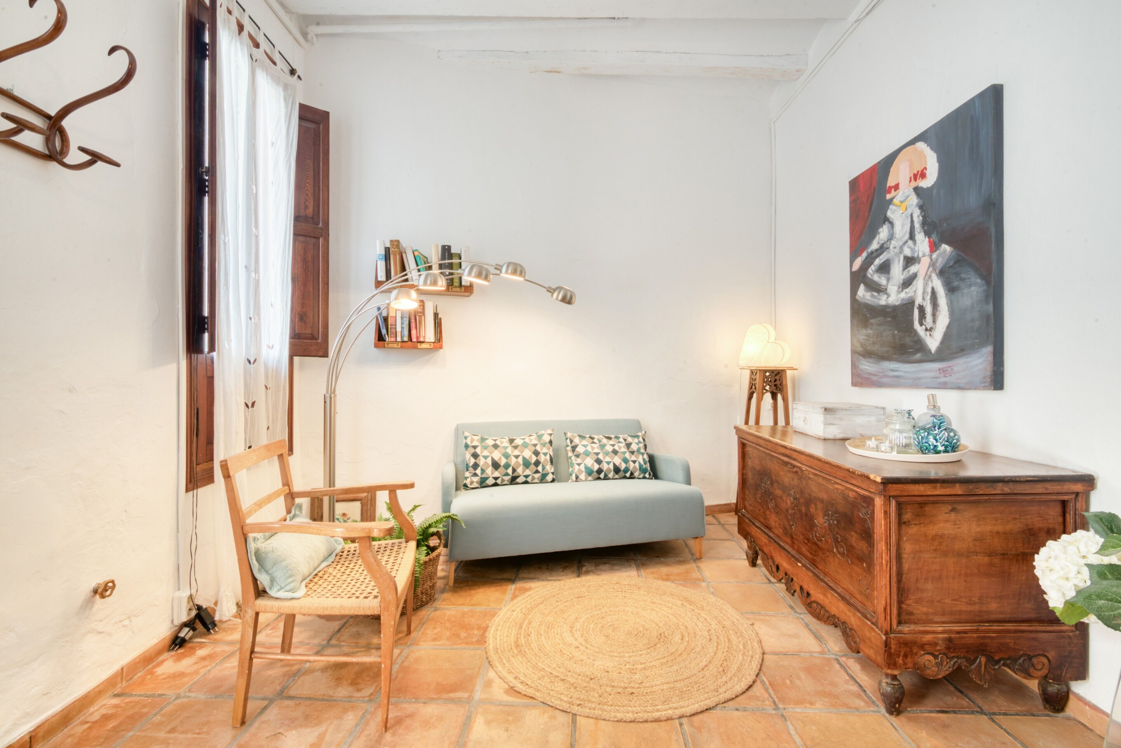Un salon comprenant un canapé, une chaise en bois, une lampe, un tableau et un meuble.