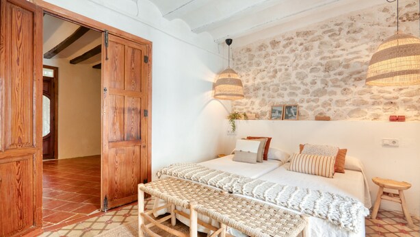 Ein Schlafzimmer mit einem Bett, einer hölzernen Bank, einer Steinwand und einer Tür.