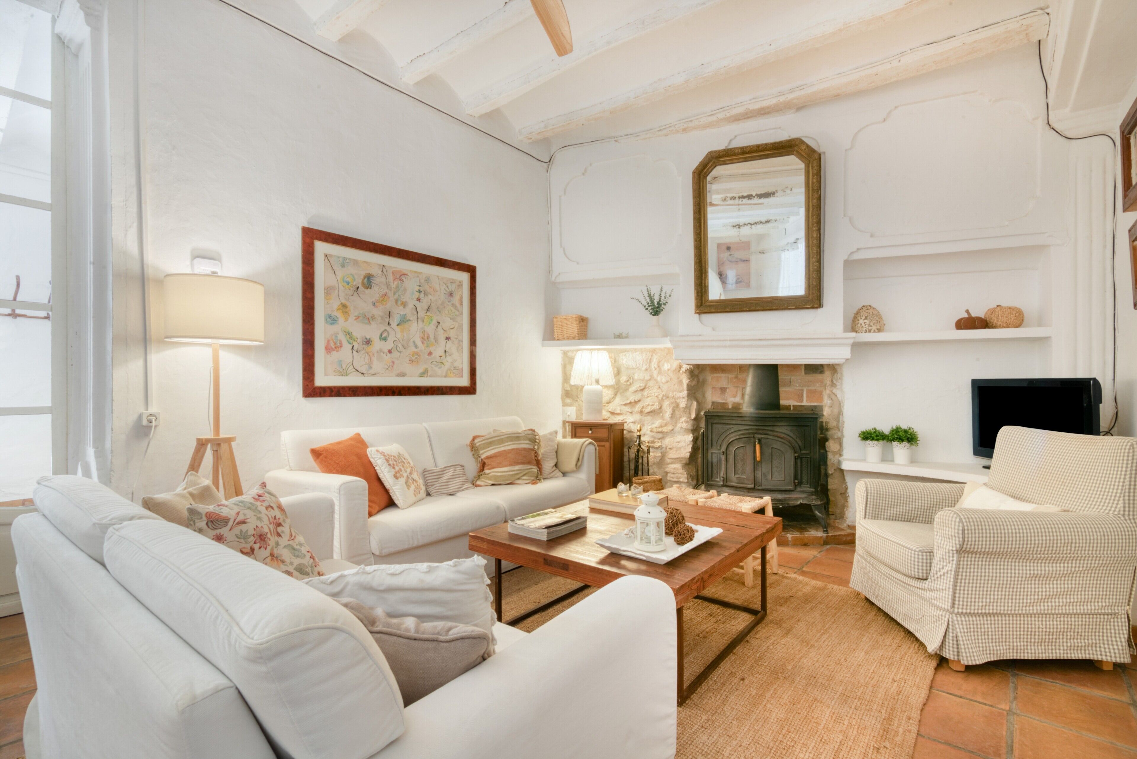 A living room with a fireplace, white furniture, and a television.