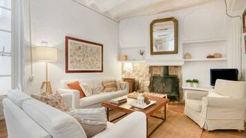 A living room with a fireplace, white furniture, and a television.