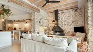 A modern living room with a stone wall, a fireplace, a sofa, and a television.
