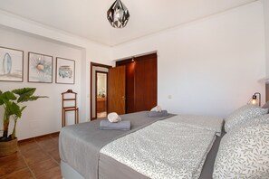 Una camera da letto con un letto, una pianta in vaso e quadri appesi al muro.