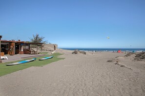 Una spiaggia con un edificio, una zona sabbiosa e un cielo sereno.