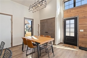 Un comedor moderno con una mesa y sillas de madera, ventanas amplias y vistas al exterior.