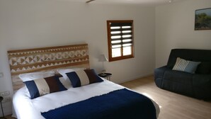 A bedroom with a bed, a window, a lamp, and a sofa.