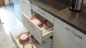 A kitchen with a built-in stove, a coffee maker, and a drawer with stacked plates.