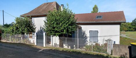 A single-story house with a fenced yard, a gravel driveway, and a clear sky.