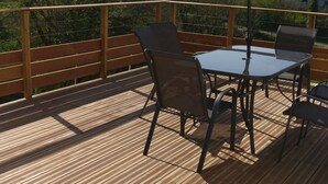 A wooden deck with a table and chairs, an umbrella, and a railing.
