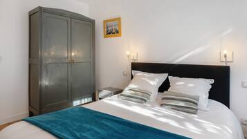 Un dormitorio con cama, armario y dos luces fijadas a la pared.