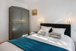 Un dormitorio con cama, armario y dos luces fijadas a la pared.