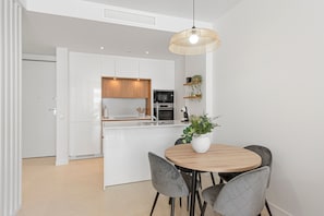 Una cocina moderna con armarios blancos, una mesa de comedor de madera y una lámpara colgante.