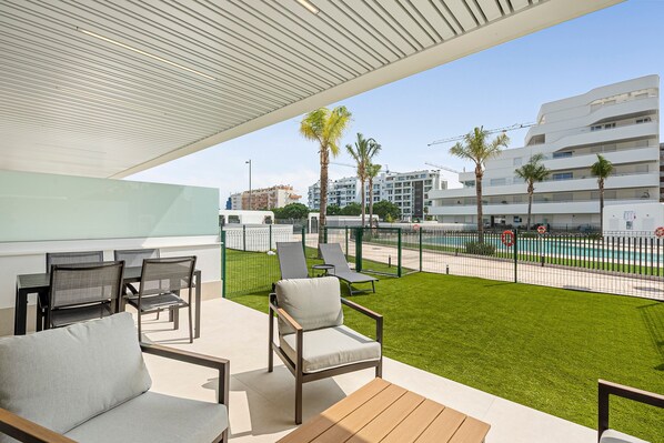 Un área de estar al aire libre con vista a la piscina, arquitectura moderna y un césped bien cuidado.