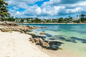 A beach with clear water, rocks, and a lighthouse in the background. - Bed and Breakfast 'Le Cocon De Sophie', Terrace and Wi-Fi (Bénodet)