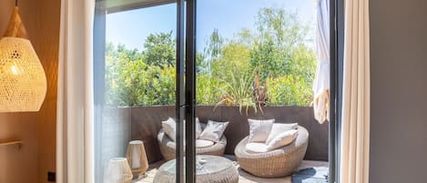A modern room with a glass door leading to an outdoor seating area with wicker furniture and a hanging light fixture.
