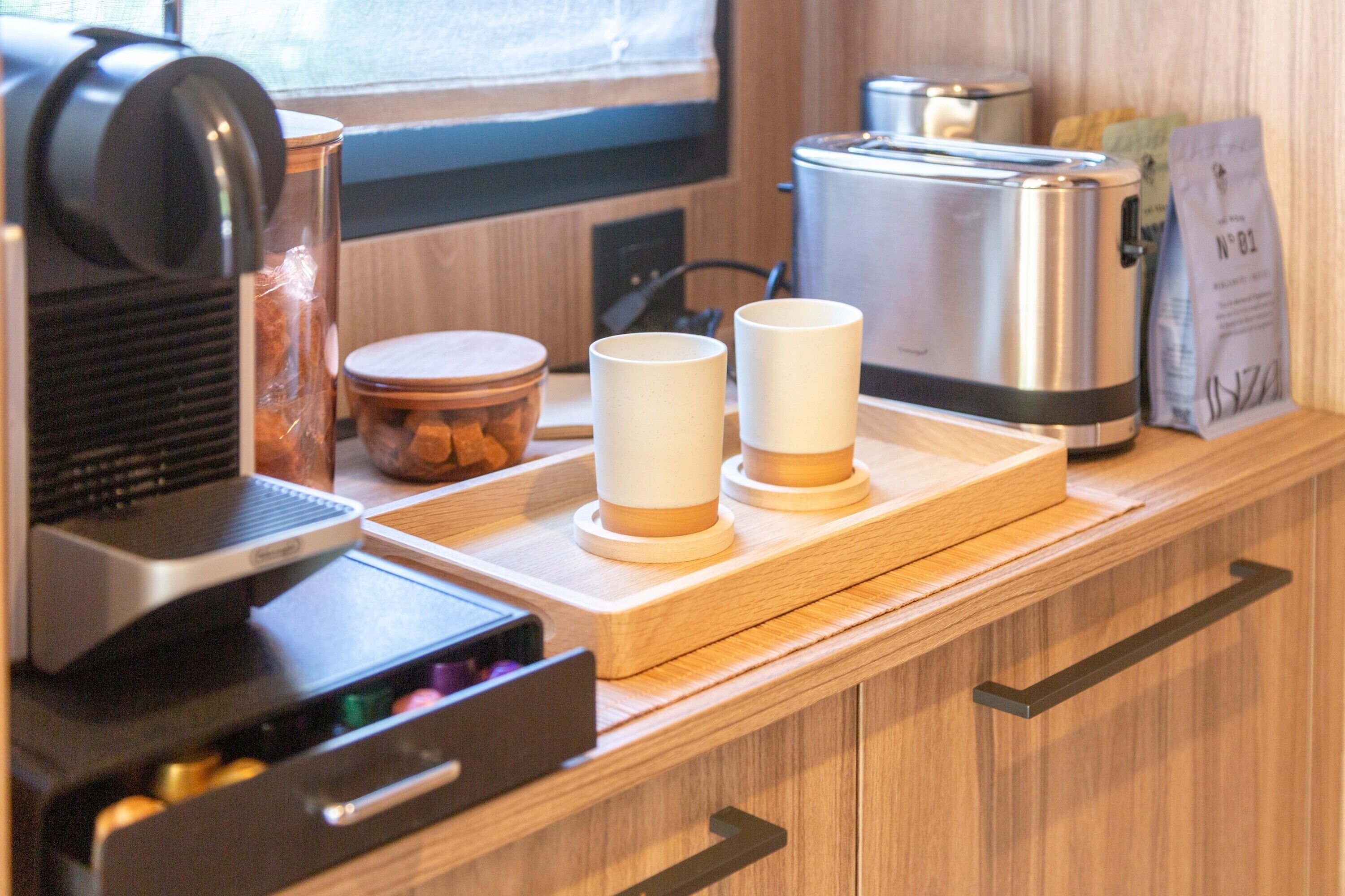 A kitchen counter with a coffee maker, a toaster, and a coffee grinder.