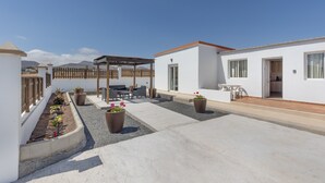 Terraza en la azotea con pérgola, zona de estar, plantas en macetas y vistas a las montañas.