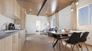 Una cocina moderna con armarios de madera, un comedor con mesa y sillas, y vistas al salón.