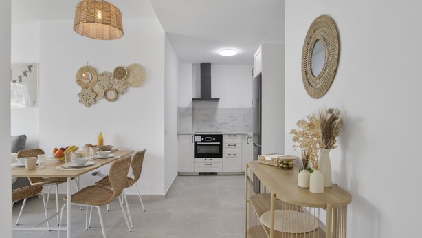 Een moderne keuken met witte kastjes, een ingebouwde oven en een hanglamp.