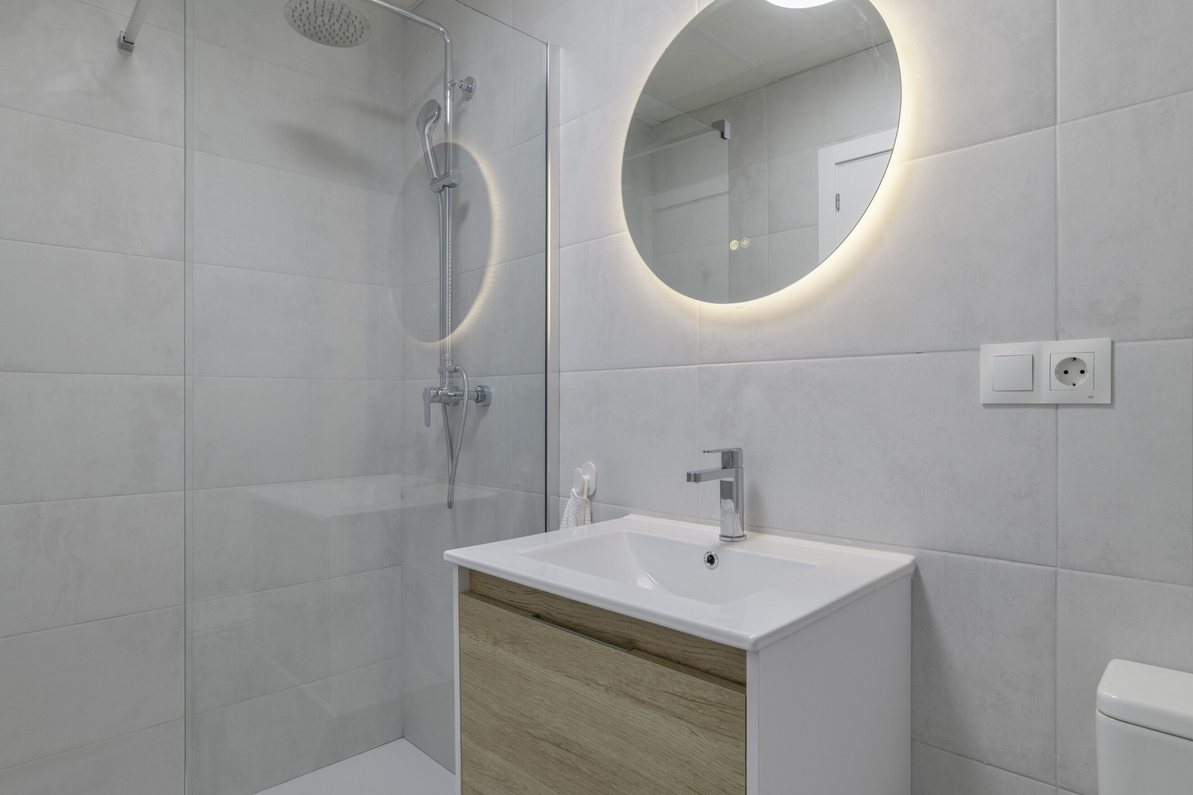 Un baño moderno con ducha, lavamanos, espejo e inodoro.