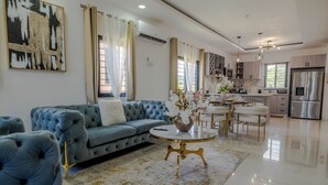 A modern living room with a blue sofa, a round coffee table, and a large abstract painting on the wall. - Rooftop Villa partial Sea view/ Mountain views (Ocho Rios)