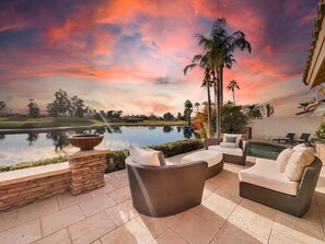 A patio with wicker furniture, a stone planter, and a view of a golf course and lake. - 8BR complex w 2 pools, lake view, sleeps 18 (Chandler)