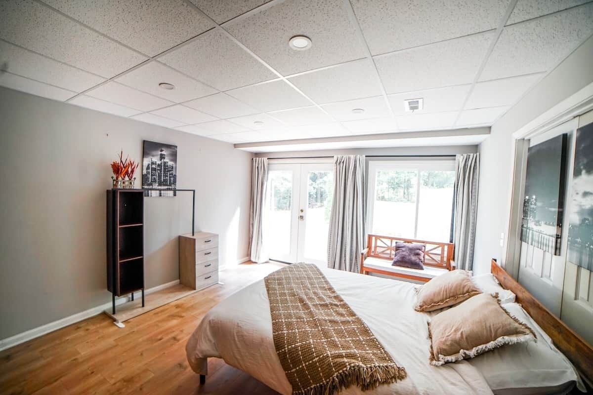 A bedroom with a bed, a wardrobe, a desk, and a window with curtains.
