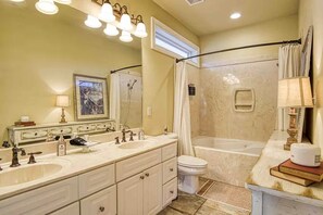 A bathroom with a double sink vanity, a bathtub, a shower, and a toilet. - Two-Story Waterfront Gem on Lake Hamilton (Hot Springs)